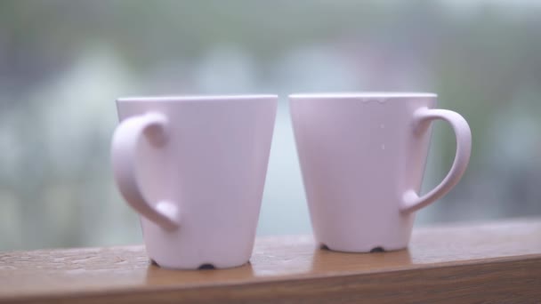 Twee witte koffie kopjes in de open lucht focus uit bekers naar de achtergrond — Stockvideo