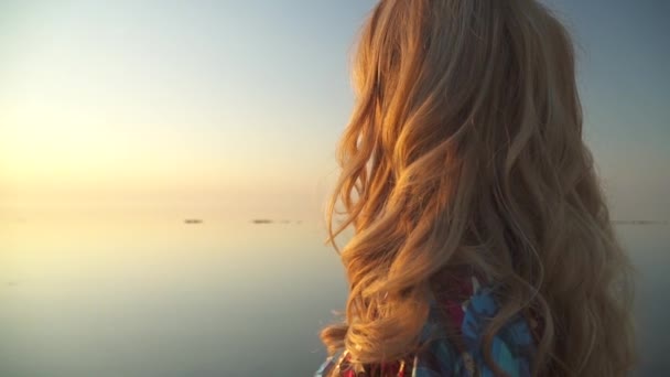 Uroczy kobieta siedzi na brzegu jezioro w promieniach słońca, picie wina ze szkła dziewczyna w lato sukienka z barkiem gołej pije wino na zewnątrz słońce w kieliszku wina — Wideo stockowe