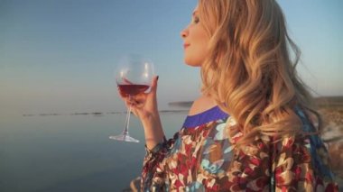 Sarışın kadın içme de deniz tarafından yakın şarap kadın döner etrafında ve göz fotoğraf makinesinde Portre