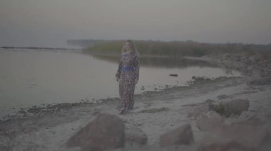 Çıplak bir omuz ile yaz giysili bir kadına Gölü sevimli kadın kesiminden açık havada kıyı kız çıplak omuz içki şarap açık havada yaz elbise içeri girer