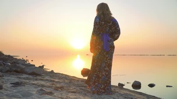 Młoda kobieta w letnią sukienkę z barkiem gołej spacery wzdłuż brzegu jeziora Ładniutka kobiety blondyn podchodzi na zewnątrz dziewczyna w lato sukienka z gołymi ramię napoje wino na zewnątrz — Wideo stockowe