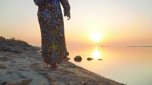 Menina em um vestido de verão com um ombro nu caminha ao longo da costa do lago Mulher bonito caminha ao ar livre Menina em vestido de verão com ombro nu bebe vinho ao ar livre — Vídeo de Stock
