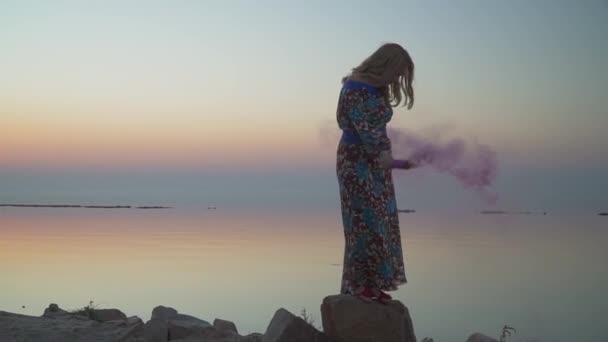 Гарна жінка тримає рожеву димну бомбу Жінка стоїть на скелі Прекрасна дівчина в літній сукні з голим плечем Симпатична жінка гуляє на відкритому повітрі Дівчина в літній сукні з голими плечима напоями вина — стокове відео