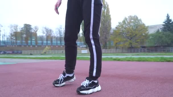 Young girl in a tight-fitting sports shirt and sweatpants does a workout at the stadium Beautiful girl with dark hair does warm-up outdoors. Sports girl doing gymnastics Healthy lifestyle — Stock Video