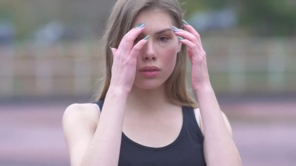 Портрет очаровательной девушки выпрямляет волосы на улице Молодая девушка с красивыми глазами и нежными губами — стоковое видео
