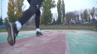 Spor giyim yakışıklı genç adam hızlandırır ve atlar kum kum kamera arka görünümü sağlıklı yaşam önüne atlayan bir Jumper'ı ayakları altından scatters