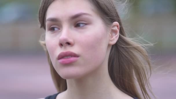 Portret pięknej młodej kobiety z długimi włosami na zewnątrz młoda dziewczyna z piękne oczy i usta przetargu, patrząc na kamery — Wideo stockowe