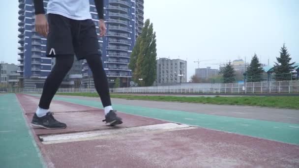 Jeune homme en vêtements de sport commence le jogging à partir d'un départ bas en plein air Beau gars de sport faisant du sport dans un stade de sport Mode de vie sain — Video