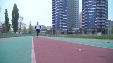 Spor giyim genç adam hızlı Stadyumu sağlıklı yaşam çalışan kamera açık havada spor muhabiri için çalışır.