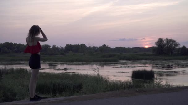 Lonely girl walking near the swamp Femme appelle par téléphone mobile Jolie jeune fille parlant au téléphone dans le contexte du coucher du soleil Passer du temps dehors — Video