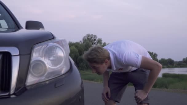 Blond man försöker fixa trasiga bil företaget av tre människor har bilolycka vänner har en rolig grupp. Bil problem — Stockvideo