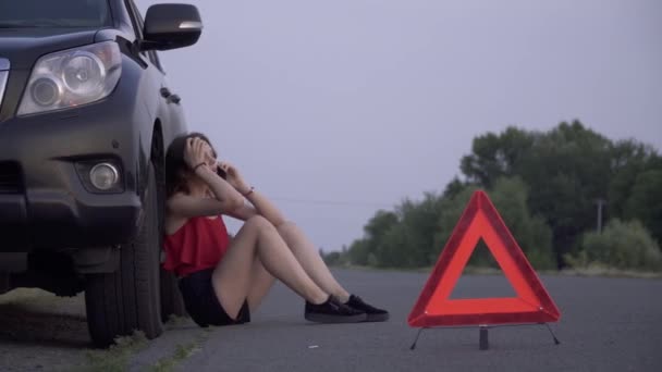 Mujer bonita está sentada cerca de coche roto Mujer joven está triste Mujer está llamando por teléfono móvil Problemas de coche — Vídeos de Stock