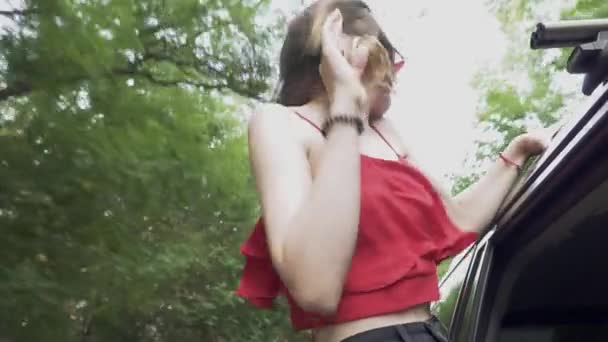 Cute girl pochyla się okno samochodu i fale jej ramiona na zewnątrz wiatr powiewa woman włosy, które pani tańczy w samochodzie — Wideo stockowe