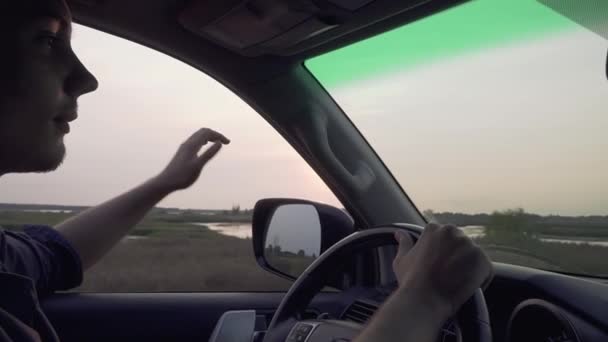 Jovem enfiou a mão pela janela e jogou com o vento dirigindo um carro na estrada à noite O homem está viajando Guy viaja de carro — Vídeo de Stock