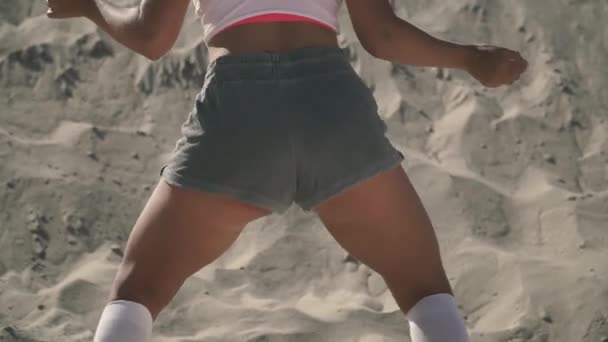 Сексуальная женщина танцует тверк на пляже Загорелая девушка двигает задницей страстно стоя на песке Прекрасная женщина танцует на пляже в коротких шортах — стоковое видео