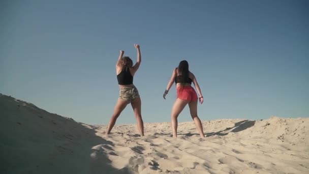 Junge sexy Mädchen mit schönen Körper tanzen twerk am Strand schöne Damen tanzen auf dem Sand heiße Damen bewegen ihre Hintern gekleidet in hellen Shorts weet Weibchen verbringen Zeit aktiv im Freien hübsch — Stockvideo