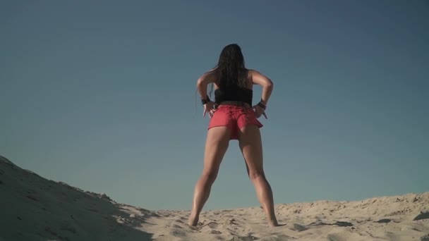 Donna sexy con bel corpo che balla twerk in spiaggia Ragazza abbronzata muove il culo in piedi sulla sabbia Femmina con un corpo attraente scuote il culo Bella ragazza balla appassionatamente Sparando da — Video Stock