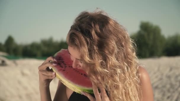 Porträt von sexy Mädchen mit wehenden Haaren, die Wassermelone im Freien essen, süßes heißes Mädchen genießt ihre Ruhe und lächelt — Stockvideo