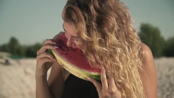 Porträt einer heißen Frau mit wehendem Haar, die Wassermelone im Freien isst, genießt ihre Ruhe und lächelt ein Stück saftige Wassermelone in den Händen eines schönen netten Mädchens — Stockvideo