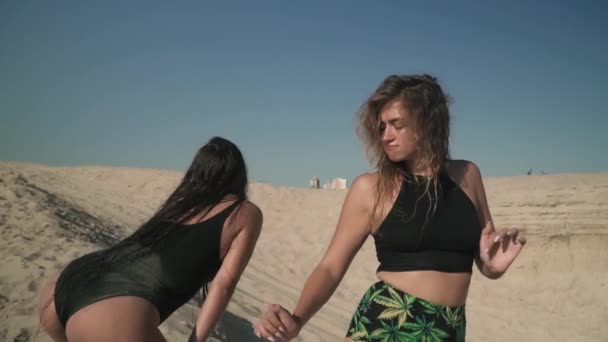 Két nő és szép szervek twerk egymás közelében a strand női tánc mozog a seggüket, állva a homok gyönyörű női tánc a szabadban szexi nők költés idő aktívan Aranyos lányok — Stock videók