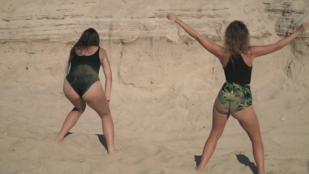 Deux femmes sexy avec des corps chauds dansant twerk près de l'autre dames déplacent leurs fesses debout sur le sable belles dames dansant en plein air femmes sexy passer du temps activement filles mignonnes danses chaudes — Video