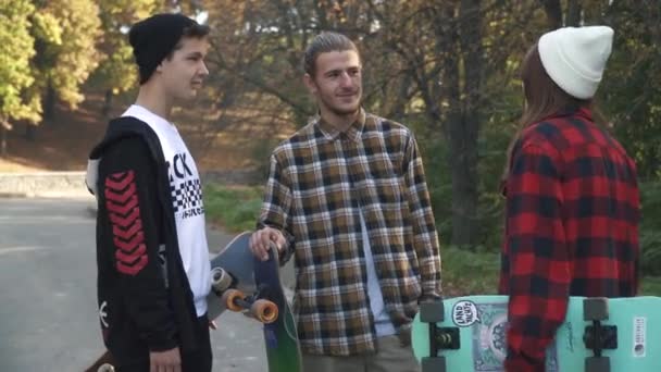 Compañía de jóvenes de pie con patinetas se comunica al aire libre. Amigos con patinetas se divierten hablando en el parque. Pasatiempos y estilo de vida . — Vídeo de stock