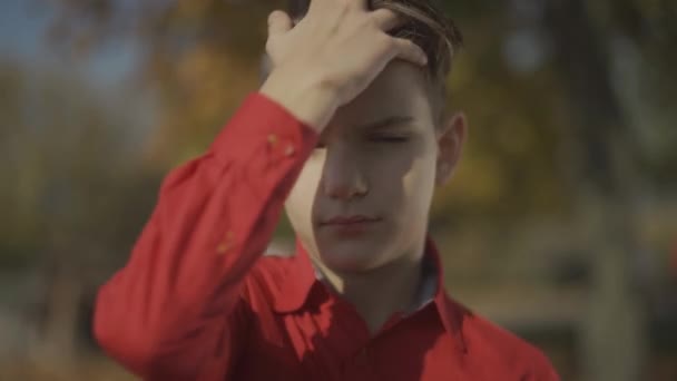 Portret van een kleine jongen corrigeert haar met zijn hand en schattige lachende. — Stockvideo