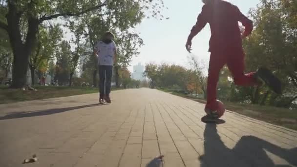 少年は、スクーターに乗っています。赤いボールを蹴る、公園で子供を実行します。 — ストック動画