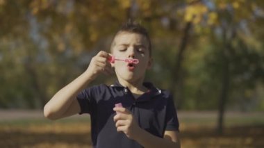 Parkta bir sabun köpüğü üfleme çocuk portresi. Çocuk açık havada oynuyor.