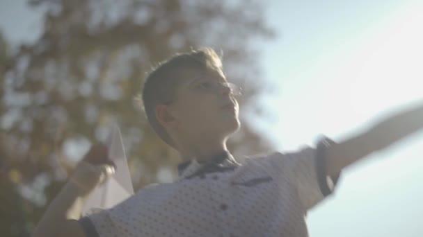 Bambino lancio aereo di carta all'aperto. Un ragazzino che gioca con un aereo di carta nel parco. Rallentatore . — Video Stock