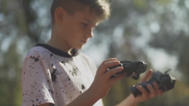 Child holds a cars remote control and toy car. Boy with a toy car outdoors. — Stock Video