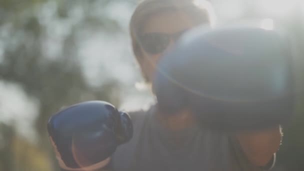 Porträtt av vuxen kvinna visar stansning flyttar i handskar på kameran närbild. Honan är glad och leende. Slow motion. — Stockvideo