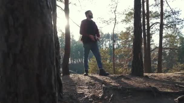 Jeune homme barbu avec une hache marcher dans la forêt et couper un arbre. Forester non rasé avec une hache à l'extérieur . — Video