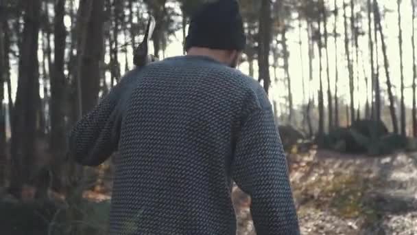 Бородач ходит по лесу с топором на плече. Форестер с топором на открытом воздухе . — стоковое видео