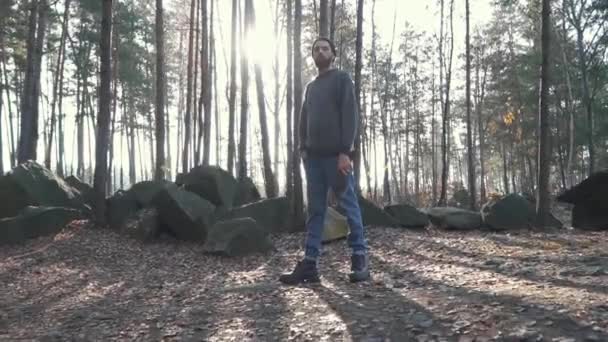 Бородатий хлопець, що стоїть у лісі, ставить сокиру на плече. Красивий жорстокий незахищений хлопець з сокирою в лісі . — стокове відео