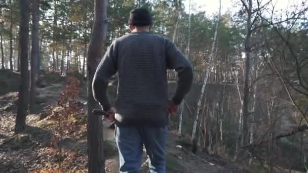 Guy is running at dangeruous road in the forest with an ax in his hands. Slow motion — Stock Video