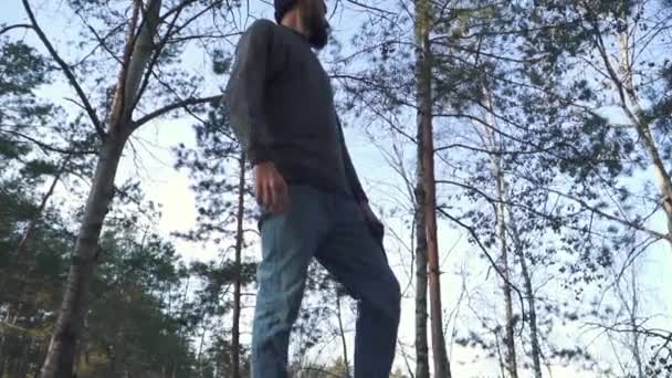 Skäggig man med en yxa promenad i skogen. Orakad forester med en yxa utomhus. — Stockvideo