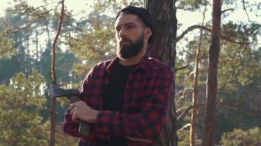 Acımasız ciddi adam ayağa ağacın yanında balta ile elinde, düşünme.