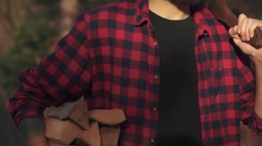 Genç adam yürüme ormandaki bir elinde kıyılmış günlükleri ve omuz balta ile sakallı. Forester yakacak odun taşır.