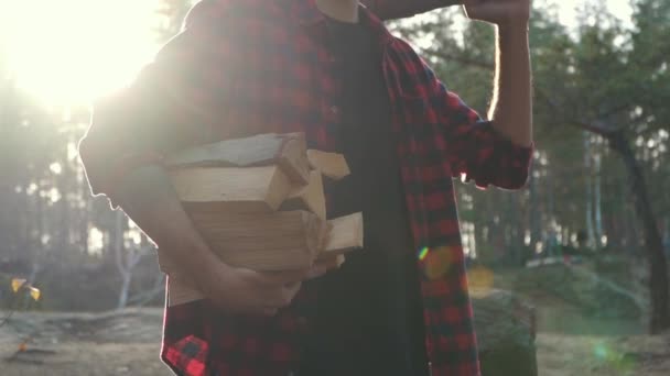 Vousáč stojan v lese s naštípané dřevo a sekerou v rukách. Forester nese dříví. — Stock video