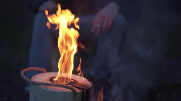 Un homme s'assoit près d'un feu de joie avec un Montréalais à la main. Forester fumant près du feu dans la forêt . — Video