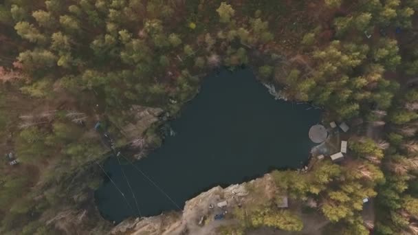 Een bovenaanzicht van een meer in het midden van het bos. Schieten vanuit de drone. — Stockvideo