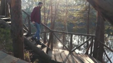 Sakallı adam elinde balta ile yürümek Gölü ile şaşırtıcı forest yakınındaki ahşap merdiven tarafından. Genç adam bir baltayla açık havada sakallı..