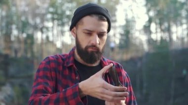 Acımasız ciddi adam açık havada balta ile. Ormanda elinde bir balta ile sakallı adam kalmak.