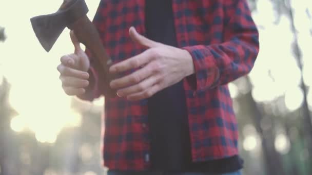 Un hombre juega con su hacha, un tipo tira hacha de una mano a otra. Tipo con un hacha al aire libre . — Vídeo de stock