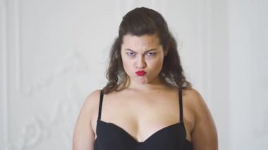 Siyah sutyen stüdyoda beyaz bir arka plan üzerinde poz şirin kız. Parlak studio poz iç çamaşırı Kızıl saçlı kadın. Sevimli kadın gülümsüyor ve saç düzeltiyor. Kız duygular gösterir. Sevinç ve