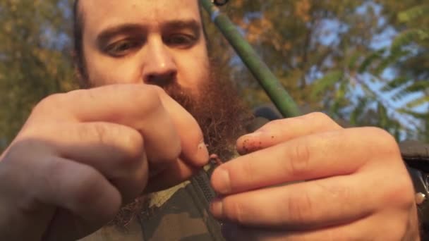 Fiskaren sätter en mask på kroken. Porträtt av vuxen fiske man med skägg. — Stockvideo