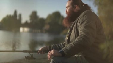 Sakallı balıkçı balıkçılık nehir kıyısında. Bir adam bir olta açık havada ile oturuyor. Nehir Balık tutma.