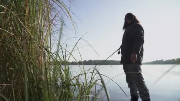 Skäggig man är fiske på flodstranden. Fiskare försöker få fisk, men det undgår. Älvfiske. — Stockvideo