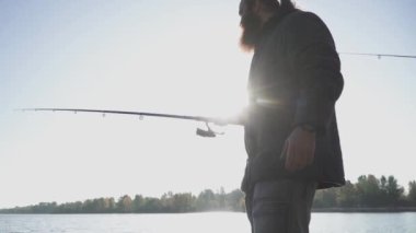 Sakallı balıkçı nehir kıyısında güneş balık tutuyor. Nehri üzerinde bir olta ile Balık tutma dostum. Nehir Balık tutma. Ağır çekim.